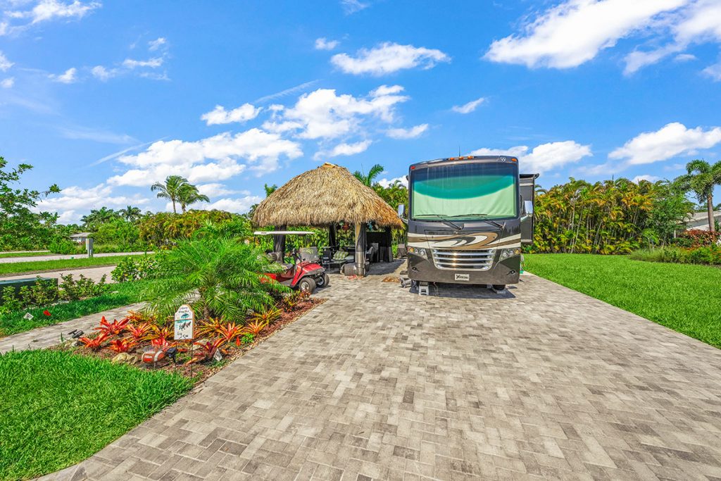 Luxury motorcoach sites with tiki huts and tropical landscaping at a Fort Myers motorcoach resort.